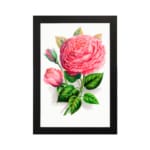 Vintage wall art with a pink rose in full bloom, a rosebud, and green leaves on a white background with a black frame. hung on the wall