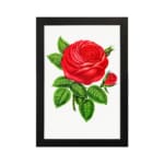 Vintage wall art of a bold red rose with green leaves on a white background, hung on the wall