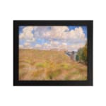 Vintage wall art of a golden grass field under a blue sky with white clouds and trees on the side hung on the wall