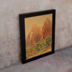Infidu Rustic Mountain Scene vintage wall art showing mountains with reddish-brown cliffs, green trees, and a golden-yellow sky. displayed on the wall