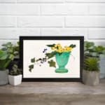Infidu vintage wall art featuring a blue-green vase with bright yellow flowers, lush green leaves, and delicate purple berries against a light background. displayed on the wall art in a black frame
