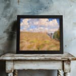 Vintage wall art of a golden grass field under a blue sky with white clouds and trees on the side displayed on the wall