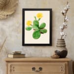 Vintage wall art featuring a cactus with yellow flowers, set against a light beige background with a black frame. displayed on the wall