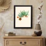 Vintage wall art of green cactus with orange flowers on beige background in a black frame displayed on the wall