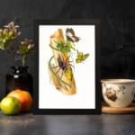 Vintage art featuring a wild nature-inspired scene with a spider, butterflies, and green leaves on a piece of bark, framed in black. displayed on the wall