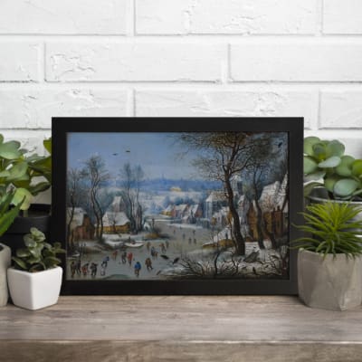 Vintage wall art showing a lively winter village scene with people skating, snowy houses, bare trees, and a soft blue sky. displayed on the wall