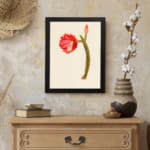 Vintage cactus flower wall art with a red bloom, pink bud, and green cactus stem on a light beige background, framed in black. displayed on the wall
