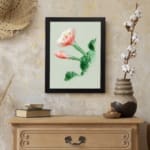 Vintage botanical wall art with a blooming flower and detailed green leaves, framed in black. displayed on the wall
