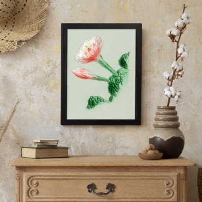 Vintage botanical wall art with a blooming flower and detailed green leaves, framed in black. displayed on the wall