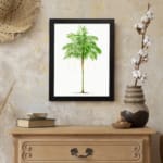 Vintage wall art of a green leaf with light yellowish-white patterns on a white background in a black frame. displayed on the wall