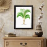 Vintage wall art of a green palm with long leaves and a split trunk framed in black. displayed on the wall