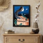 Vintage wall art of a ghostly face with long black hair emerging from a wooden barrel, with a dramatic night sky background. displayed on the wall in a black frame