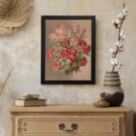 Vintage wall art of red roses and pink flowers with green leaves on a beige background, framed in black. displayed on the wall
