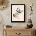 Black-and-white vintage sketch of a horse rearing with a snake wrapped around its body, framed in black. displayed on the wall