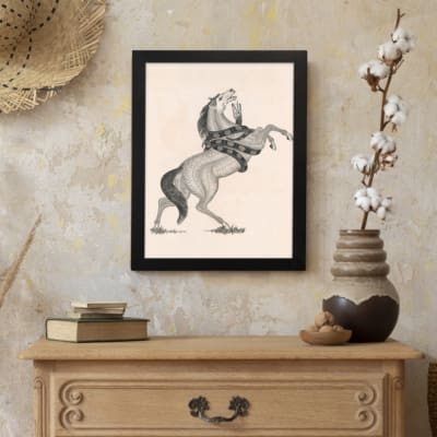 Black-and-white vintage sketch of a horse rearing with a snake wrapped around its body, framed in black. displayed on the wall