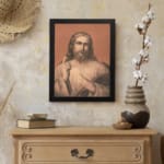 Vintage wall art of Jesus Christ holding a book, raising one hand, with soft, muted colors and a warm terracotta background. displayed on the wall