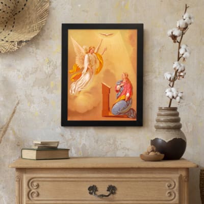 Vintage wall art of an angel and praying woman with glowing light and warm cloudy sky background. displayed on the wall