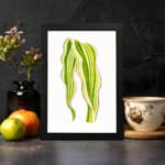 Vintage wall art of a single leaf with flowing, wavy shapes in green and yellow, framed in black on a white background. displayed on the wall
