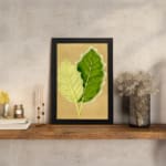 Infidu vintage wall art featuring two detailed botanical leaves in light and dark green against a soft beige background. displayed on the wall art in a black frame