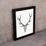 Rustic deer skull vintage wall art with black-and-white design on a grainy background. displayed on the wall in a black frame