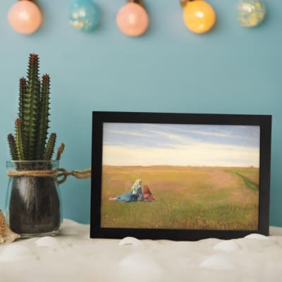 Vintage wall art of two women sitting in an open field under a bright, cloudy sky with soft green and yellow tones. displayed on the wall