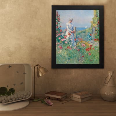 Vintage wall art of a woman in a garden with pastel flowers, ocean view, and soft countryside details. displayed on the wall