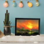 Infidu vintage ocean sunset wall art with fiery sky, waves, and glowing sun in bold colors of orange, red, yellow, and green. displayed on the wall