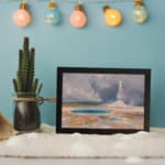 Vintage art of hot spring and erupting geyser with cloudy sky. displayed on the wall