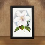Vintage wall art of a white flower with soft purple hues and green leaves, framed in black. displayed on the wall