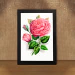 Vintage wall art with a pink rose in full bloom, a rosebud, and green leaves on a white background with a black frame. displayed on the wall
