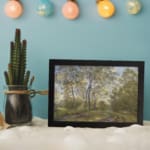 Infidu vintage wall art showing a peaceful forest path in soft green tones with trees, a dirt trail, and a blue sky. displayed on the wall