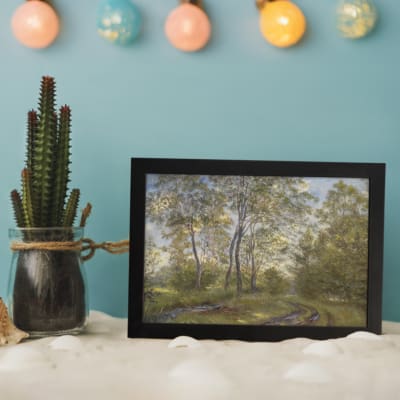 Infidu vintage wall art showing a peaceful forest path in soft green tones with trees, a dirt trail, and a blue sky. displayed on the wall