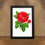 Vintage wall art of a bold red rose with green leaves on a white background, displayed on the wall