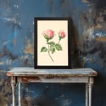 Infidu vintage wall art with two pink rosebuds and green leaves on a cream background in a black frame. displayed on the wall