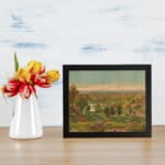 Vintage countryside wall art with soft colors, green hills, and a peaceful sky. displayed on the wall