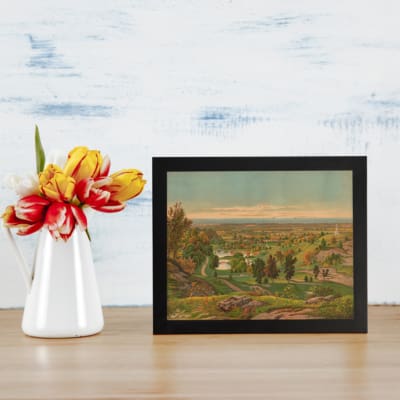 Vintage countryside wall art with soft colors, green hills, and a peaceful sky. displayed on the wall