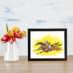 Vintage horse racing wall art with two galloping horses and jockeys on a bold yellow background. displayed on the wall