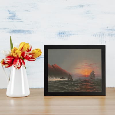 Vintage wall art showing a dramatic ocean sunset with tall waves, sailing ships, glowing cliffs, and a cloudy sky. displayed on the wall