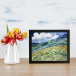 Infidu vintage countryside wall art with green hills and swirling blue sky. displayed on the wall