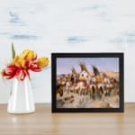Vintage wall art of Native American tipi scene with horses, people, and earthy tones in a peaceful open landscape. displayed on the wall