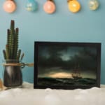 Vintage wall art of a sailing ship on a stormy sea with dark waves and a dramatic, cloudy sky. displayed on the wall