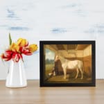 Vintage wall art of a white horse standing calmly inside a rustic wooden stable with a peaceful countryside view. displayed on the wall