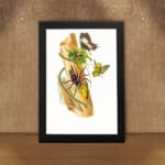 Vintage art featuring a wild nature-inspired scene with a spider, butterflies, and green leaves on a piece of bark, framed in black. displayed on the wall