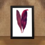 Vintage wall art featuring two red and purple leaves with a white background and black frame. displayed on the wall