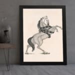Black-and-white vintage sketch of a horse rearing with a snake wrapped around its body, framed in black. displayed on the wall