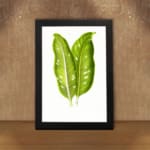 Vintage wall art featuring two large tropical green leaves with white lines and holes, set against a plain white background in a black frame. displayed on the wall