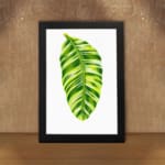 Bright green leaf with light and dark tones on white background in a black frame – vintage wall art by Infidu. displayed on the wall