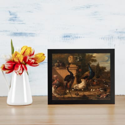 Vintage wall art of exotic birds, including peacocks, in a classical architectural setting with trees, sky, and elegant columns. displayed on the table in a black frame