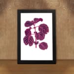 Vintage wall art showing a purple leafy plant with pink veins on a white background, framed in black. displayed on the wall