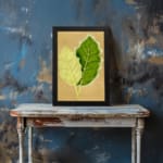 Infidu vintage wall art featuring two detailed botanical leaves in light and dark green against a soft beige background. displayed on the wall art in a black frame